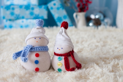 Two handmade snowmen with Christmas background on white fur